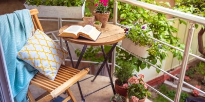 Krásná terasa nebo balkon s malým stolem, židlí, knihou a květinami