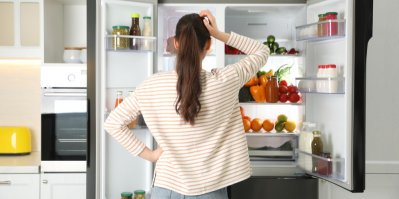 Mladá žena v blízkosti otevřené lednice v kuchyni