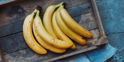 Trs banánů na dřevěné desce s modrým prostíráním 