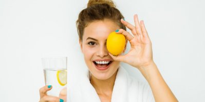 Žena se sklenicí vody a citronem v ruce