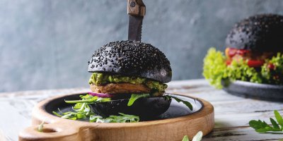 Černý burger na dřevěném prkénku