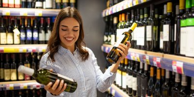 Žena drží v supermarketu lahve vína 