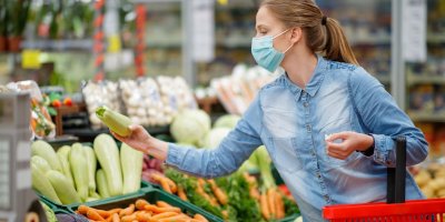Žena s plným nákupním vozíkem vybírá potraviny v supermarketu