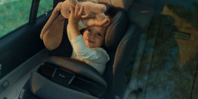 Malá holčička sedí v autosedačce Cybex Anoris T i-Size a hraje si s plyšovou hračkou