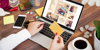 Žena drží platební kartu a prohlíží si stránky e-shopu na notebooku