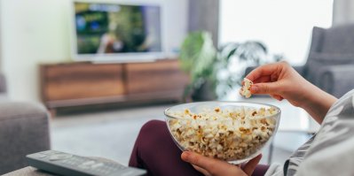 Člověk sleduje televizi s mísou popcornu