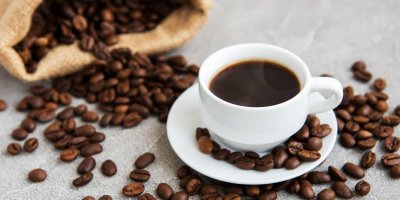 Šálek kávy a vysypaná kávová zrna