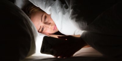 Žena s telefonem v posteli v noci