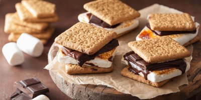 Čtyři dezerty s’mores z marshmallows, sušenek a čokolády na kulatině