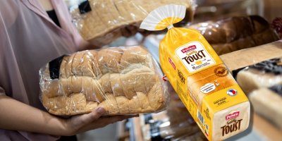Žena drží v supermarketu v ruce toustový chléb