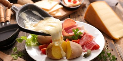 Roztavený sýr je poléván na brambory a salám na talířku
